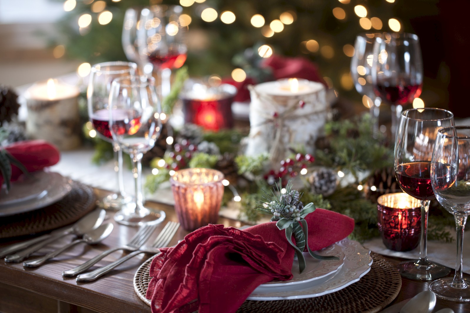 A festive table setting with red wine glasses, candles, and holiday decorations, creating a warm and inviting atmosphere.