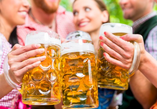 People are clinking large beer mugs, celebrating in a festive atmosphere.