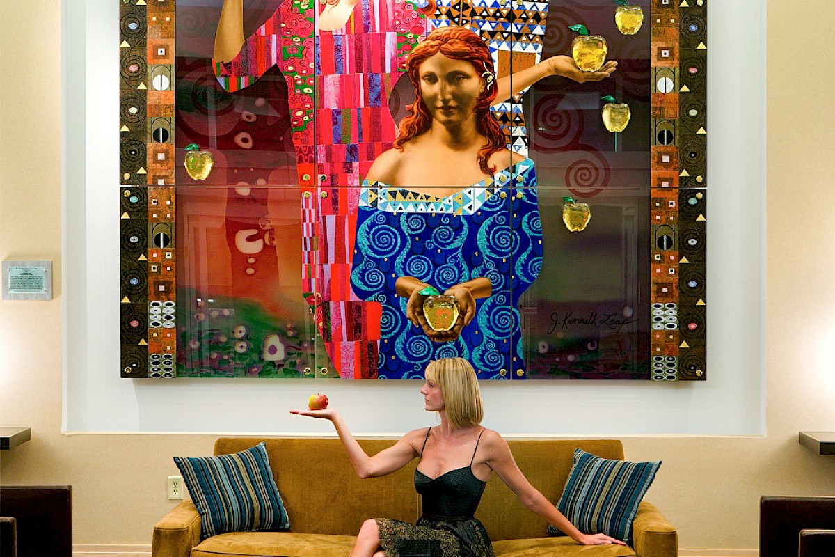 Photo of woman siting in a sofa holding an apple like the art frame behind here in a luxury modern room
