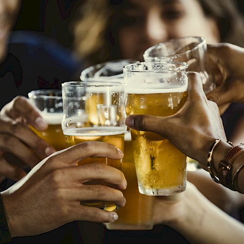 A group of people clinking glasses of beer in a toast, creating a celebratory and cheerful atmosphere.