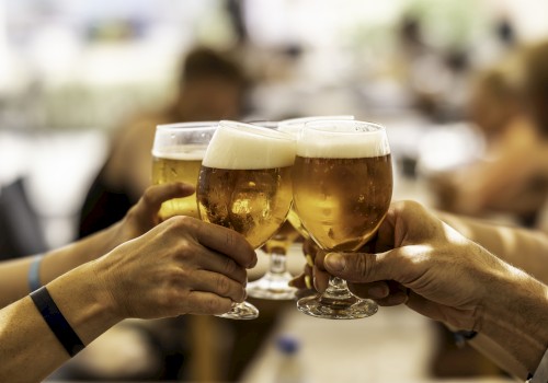 A group of people clinking glasses of beer in a toast, celebrating together in a social setting.