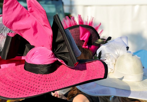 A collection of colorful, elaborate hats with feathers and ribbons against a blurred background.