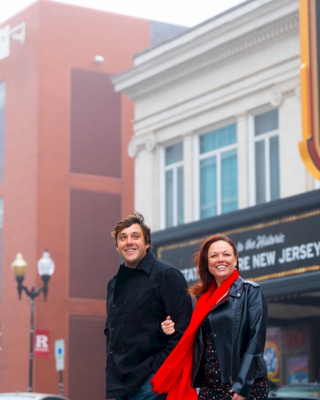 A couple is walking outside an old theater with a marquee that reads 