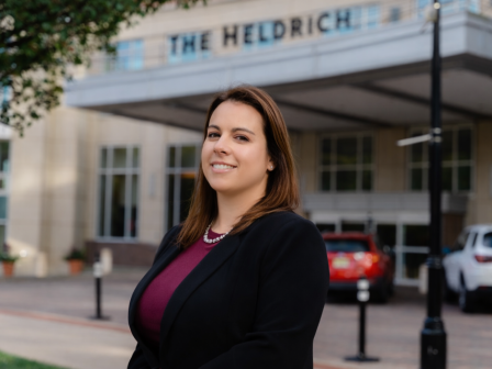 A confident woman stands outside a building with 